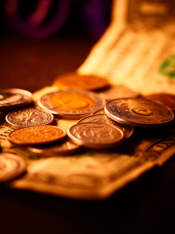 A detailed close-up of assorted currency coins and paper bills in warm lighting, emphasizing financial themes.